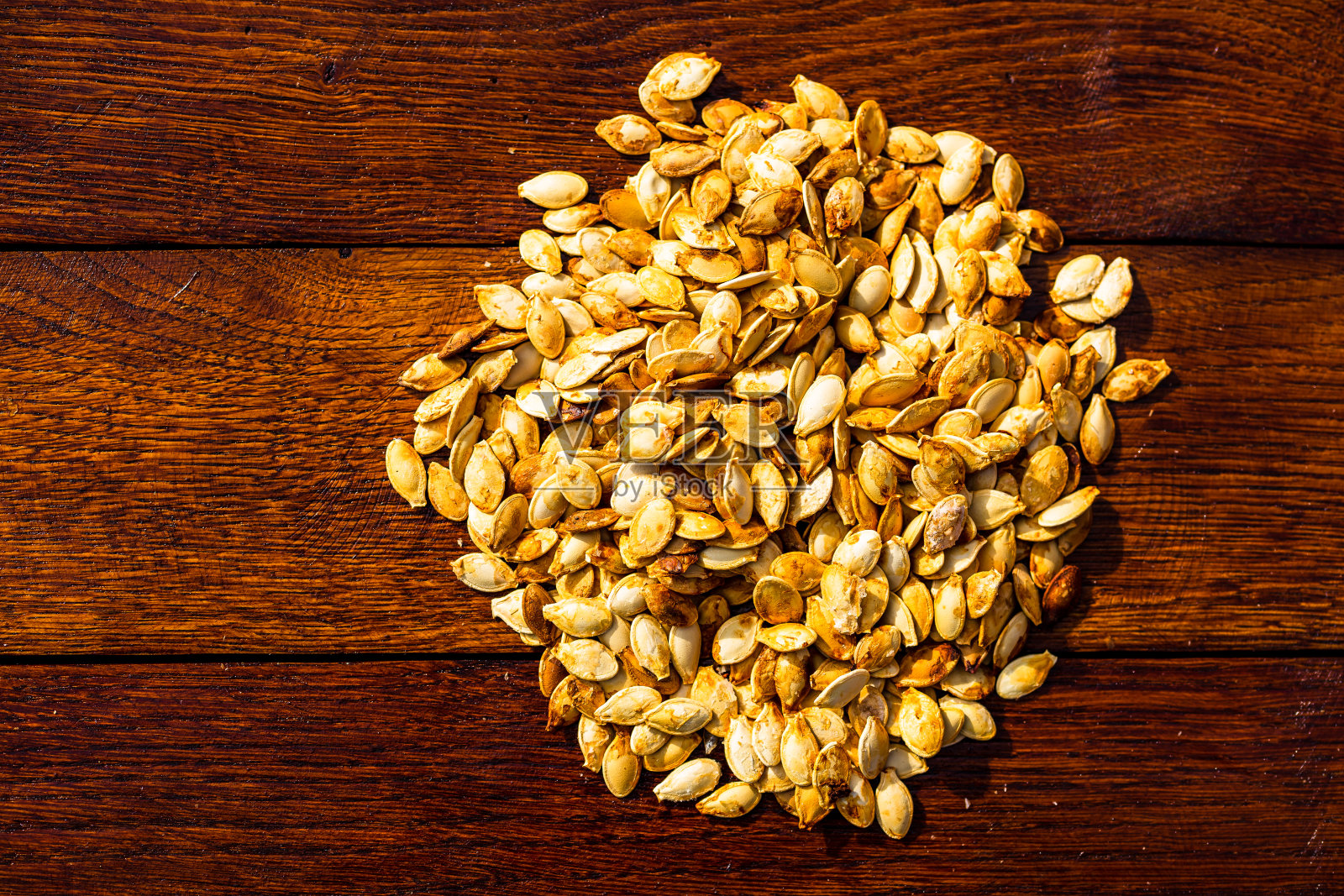 木桌上的烤咸南瓜子照片摄影图片