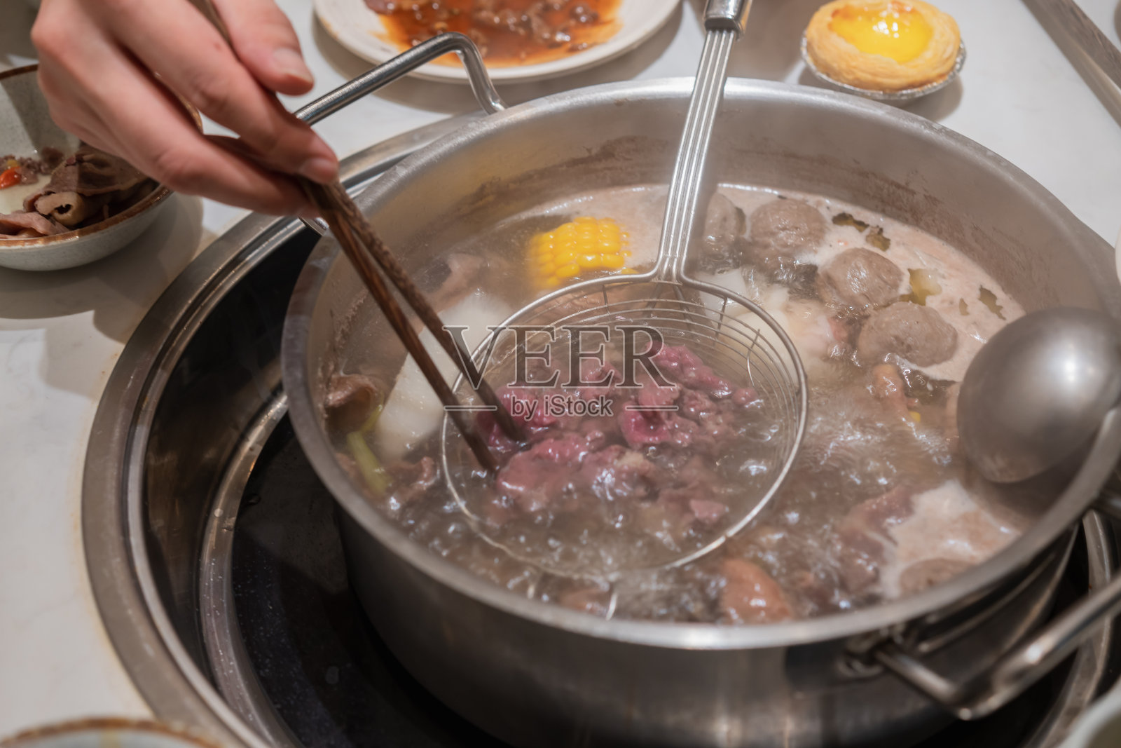 一双手用胶水和筷子夹在火锅里,牛肉照片摄影图片