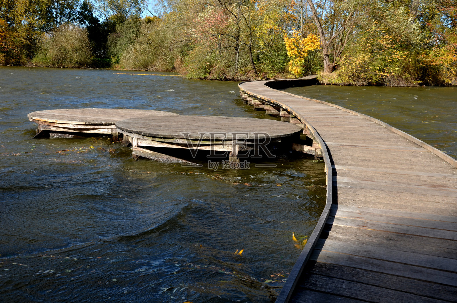由木板制成的浮动走道。踩高跷上的狭窄弯曲的小路被推入湖底,高出湖水。没有栏杆。更多的设计走道由单独的圆形板制成。秋天防波堤照片摄影图片