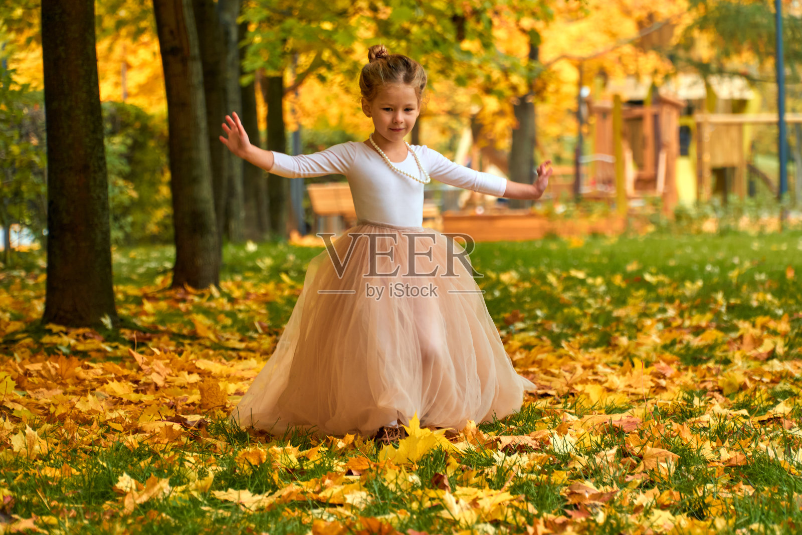 小公主在黄秋穿着一条松软的裙子。橙色的绿色和一个快乐的孩子在外面玩耍。在你家附近的新公园里进行有趣的户外活动。童年的概念。照片摄影图片