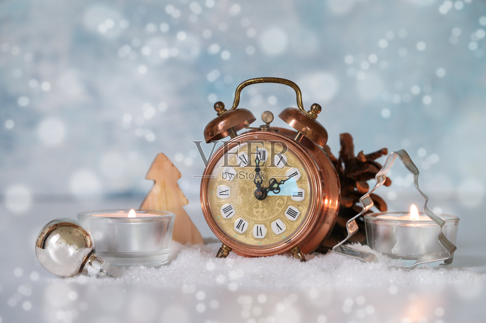 改变到冬天的时间,复古闹钟后退一小时,蜡烛和季节性的装饰以雪白的浅蓝色为背景,复制空间照片摄影图片