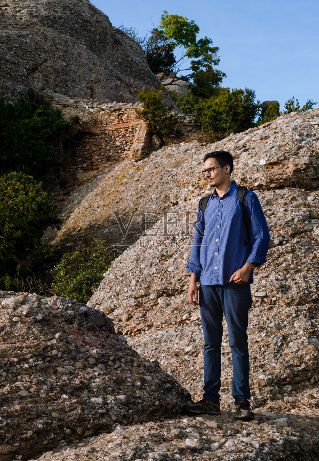 年轻的游客站在岩石上四处张望。照片摄影图片