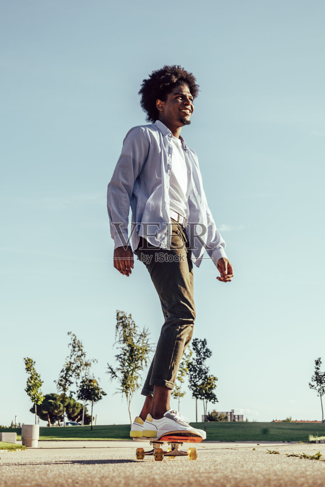 年轻的非洲男子在天空背景上滑滑板照片摄影图片