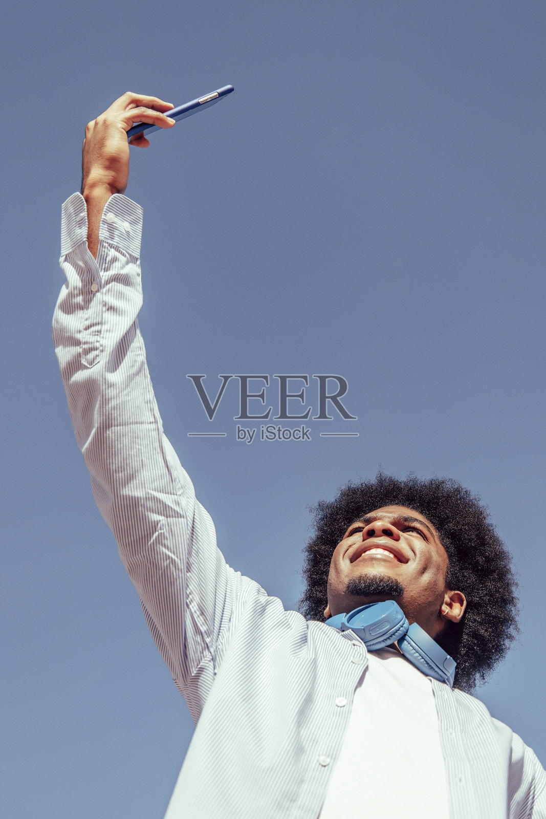 年轻非洲裔美国人的垂直肖像与非洲式头发自拍。视图从下面照片摄影图片