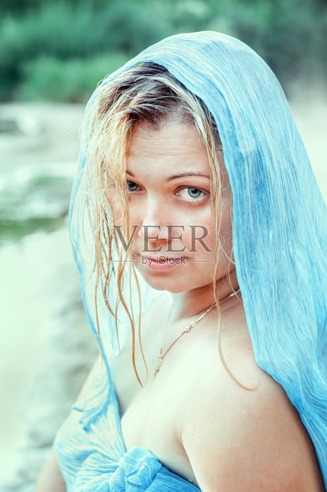 一个年轻漂亮的女人,湿着头发,头上戴着一条蓝色的披肩。漂亮的蓝眼睛女人看着镜头照片摄影图片