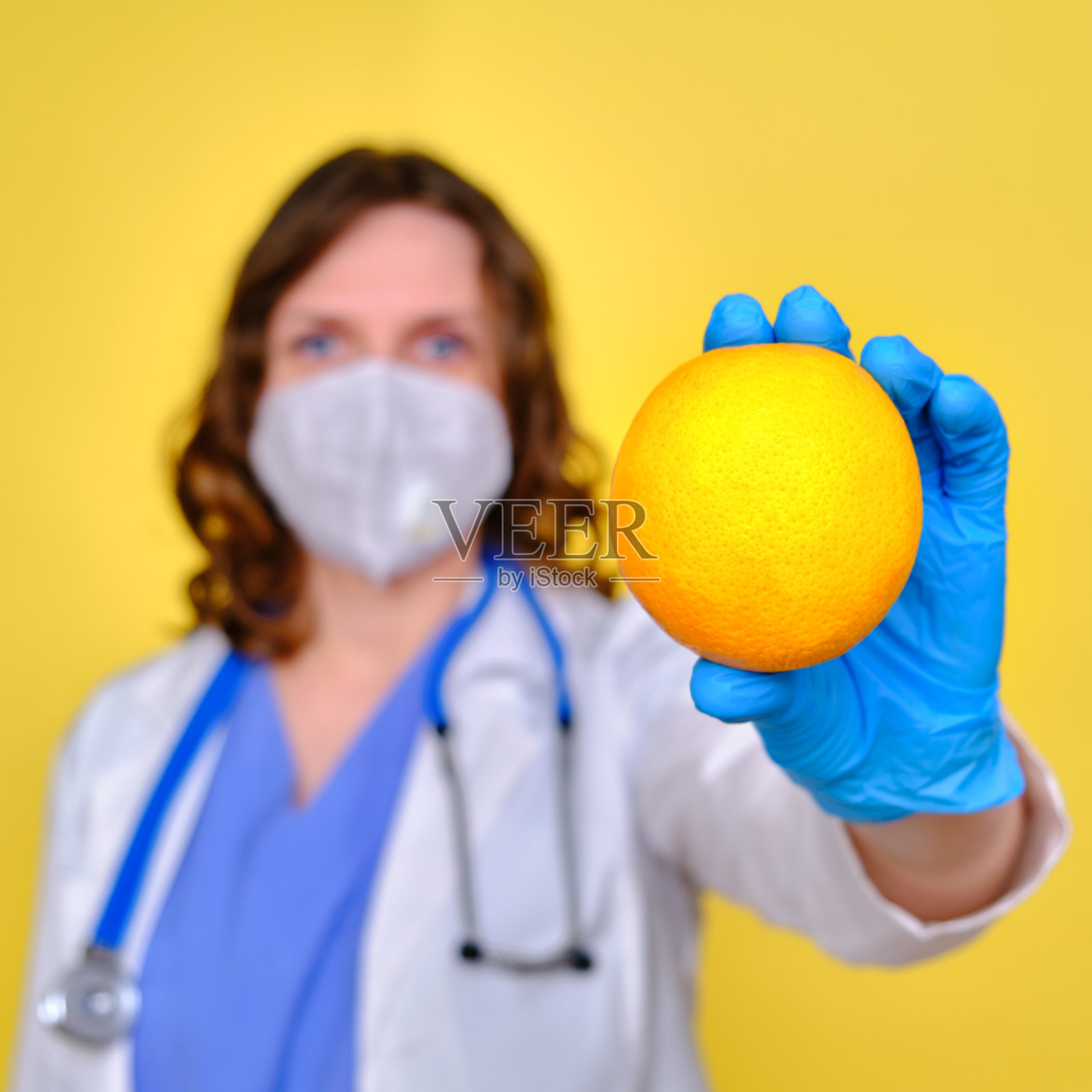 女医生拿着橙色的水果,黄色的画室背景照片摄影图片