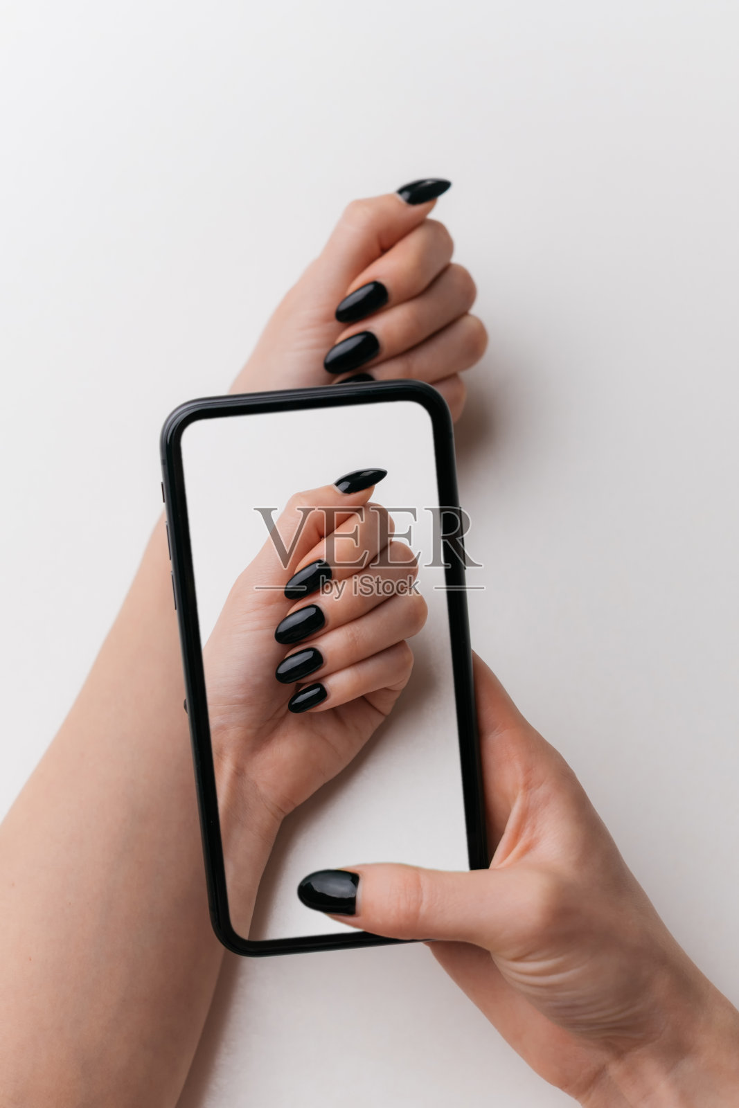 一个女人用手机拍下了自己的美甲。照片摄影图片