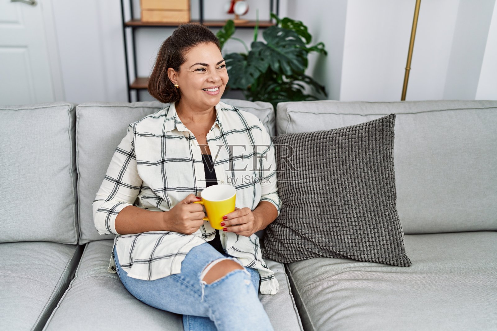 中年西班牙妇女微笑自信地在家里喝咖啡照片摄影图片