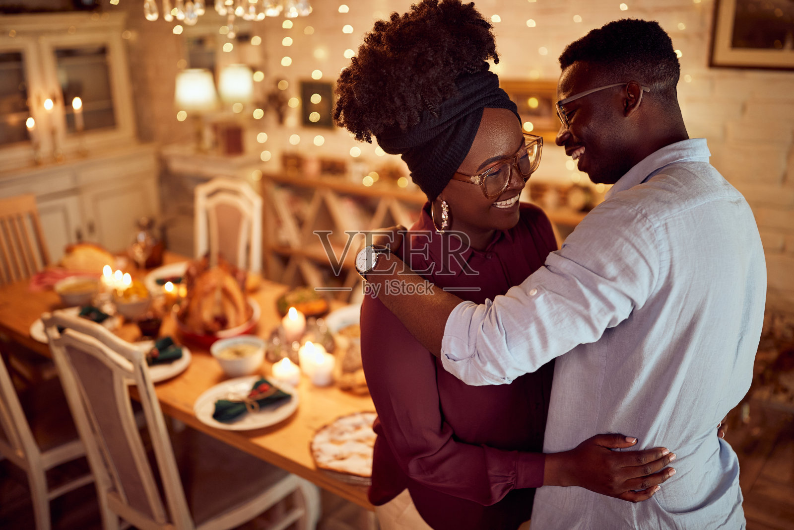 在家里的餐厅庆祝感恩节时,拥抱了一对快乐的黑人夫妇。照片摄影图片