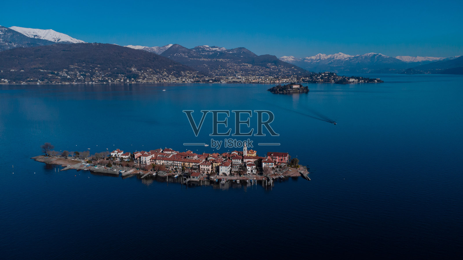 一个阳光明媚的冬日,意大利马乔拉湖上的优索拉全景图。宏伟的山脉与积雪可见的背景。照片摄影图片