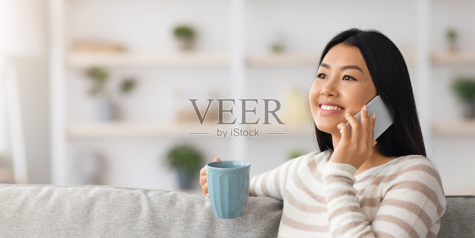 在家喝茶打电话的快乐亚洲年轻女人照片摄影图片