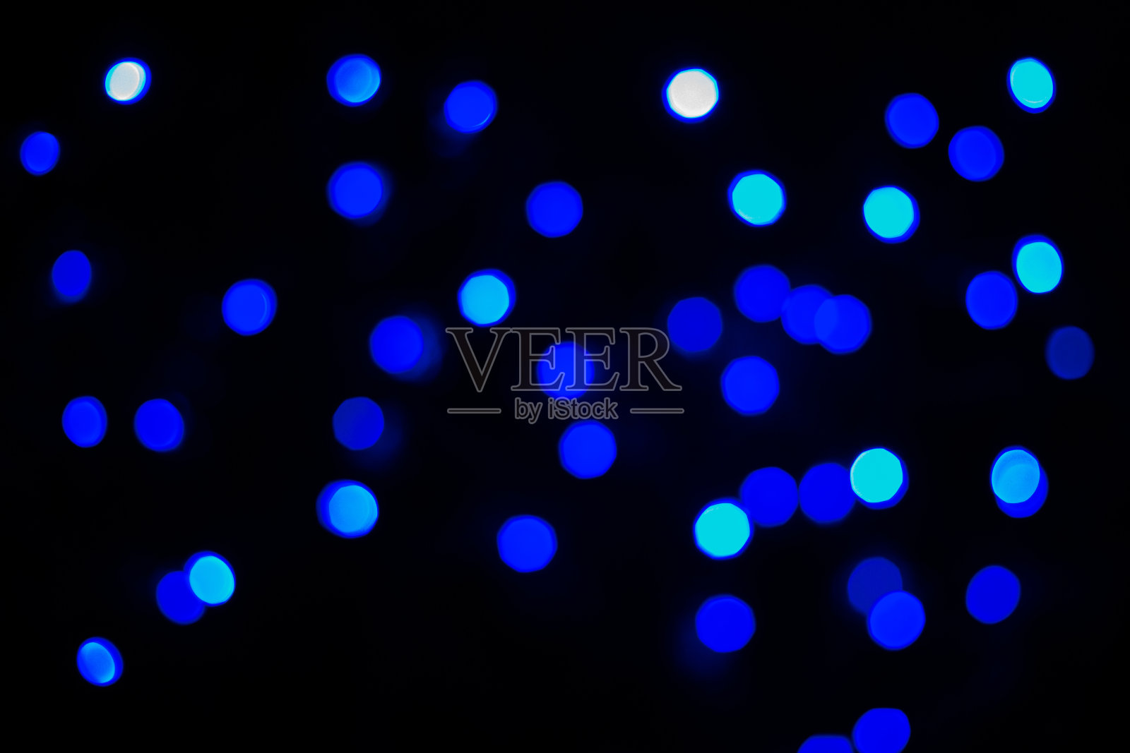 在黑色背景上散焦的蓝色抽象散景灯。照片摄影图片