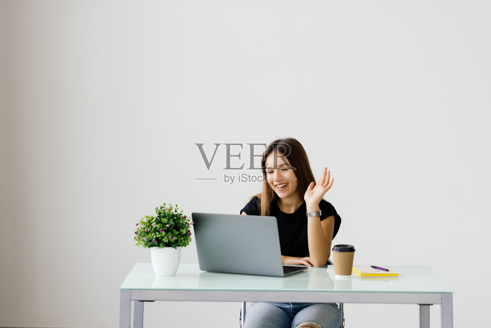 快乐的女人穿着白衬衫微笑和挥手的笔记本电脑,同时在办公室通话或视频聊天照片摄影图片