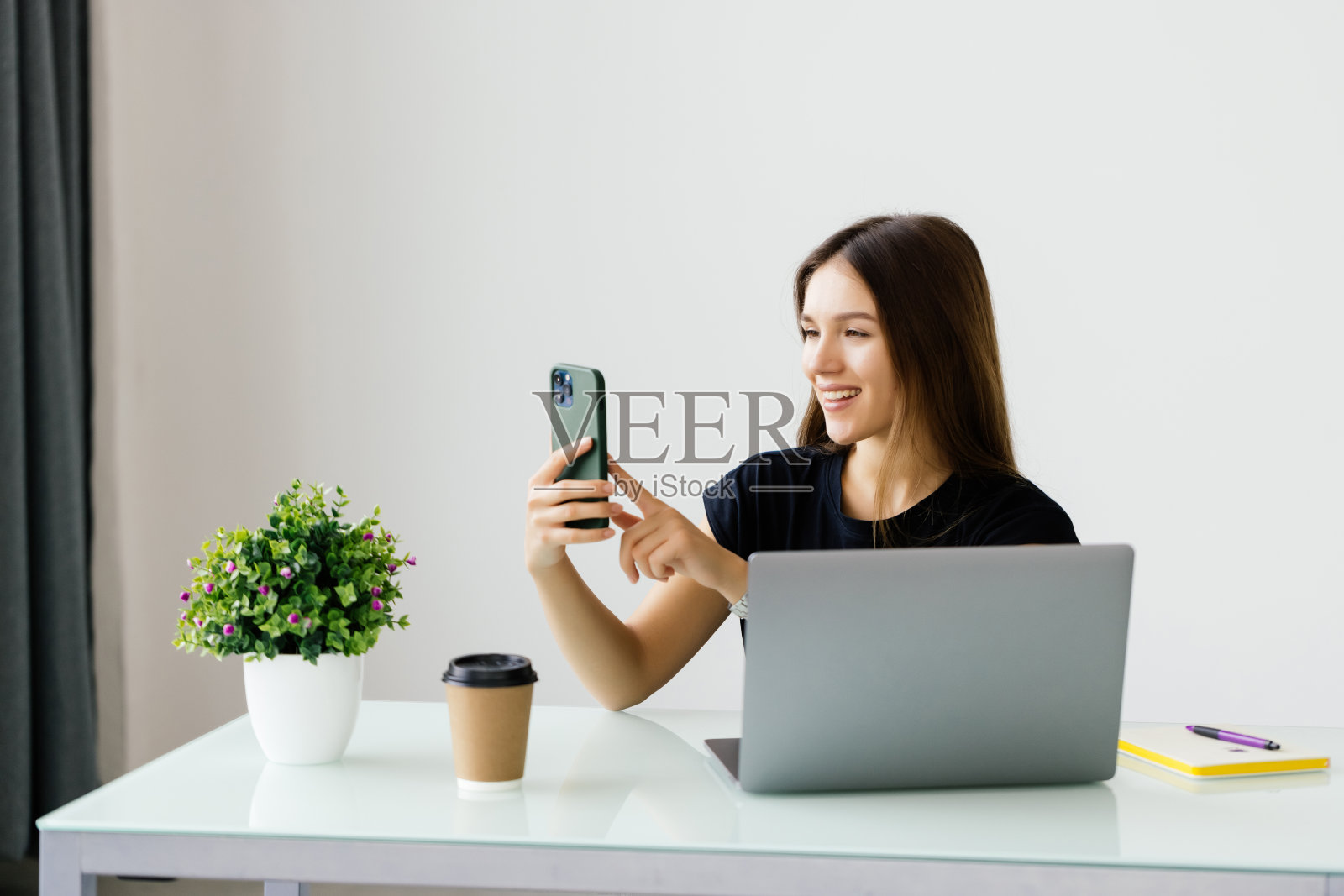 年轻女子在家中办公室拿着电话看屏幕掌上键盘照片摄影图片