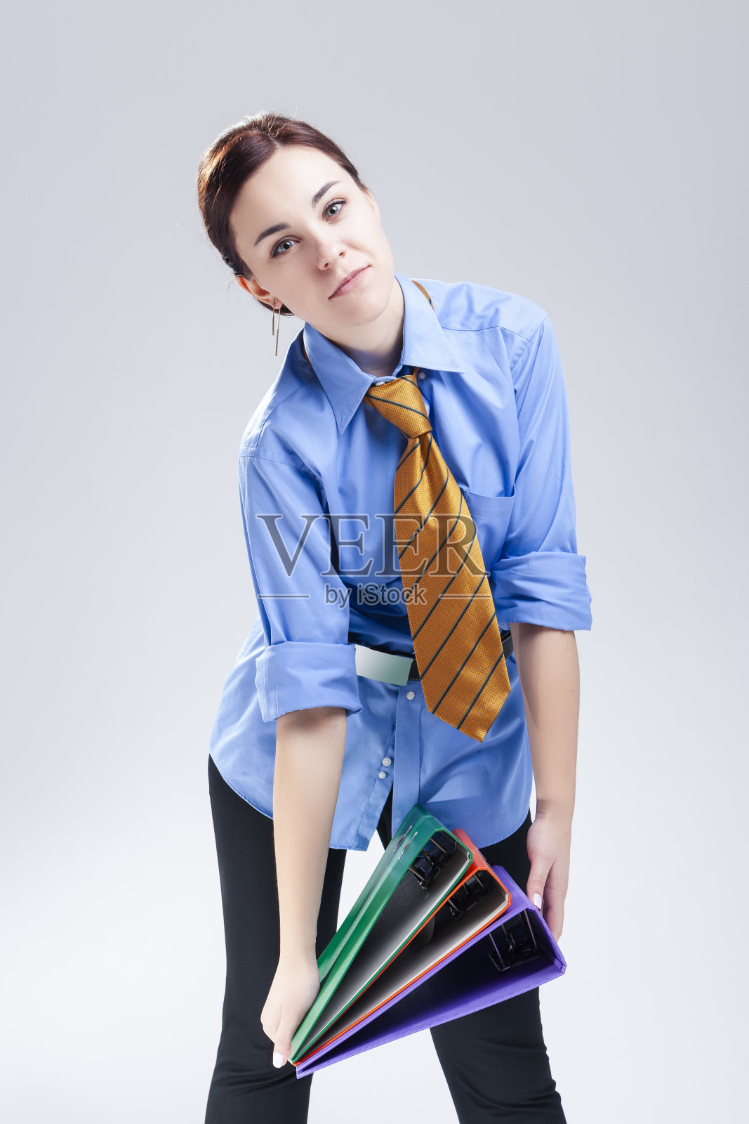 商人的概念。年轻的黑发白人女子在官方蓝色衬衫和领带与文件夹堆摆姿势。垂直的图像照片摄影图片