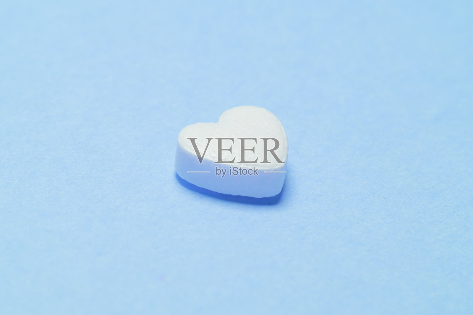 蓝色背景上的心形药丸。治疗心脏,血管和肺的药物。照片摄影图片