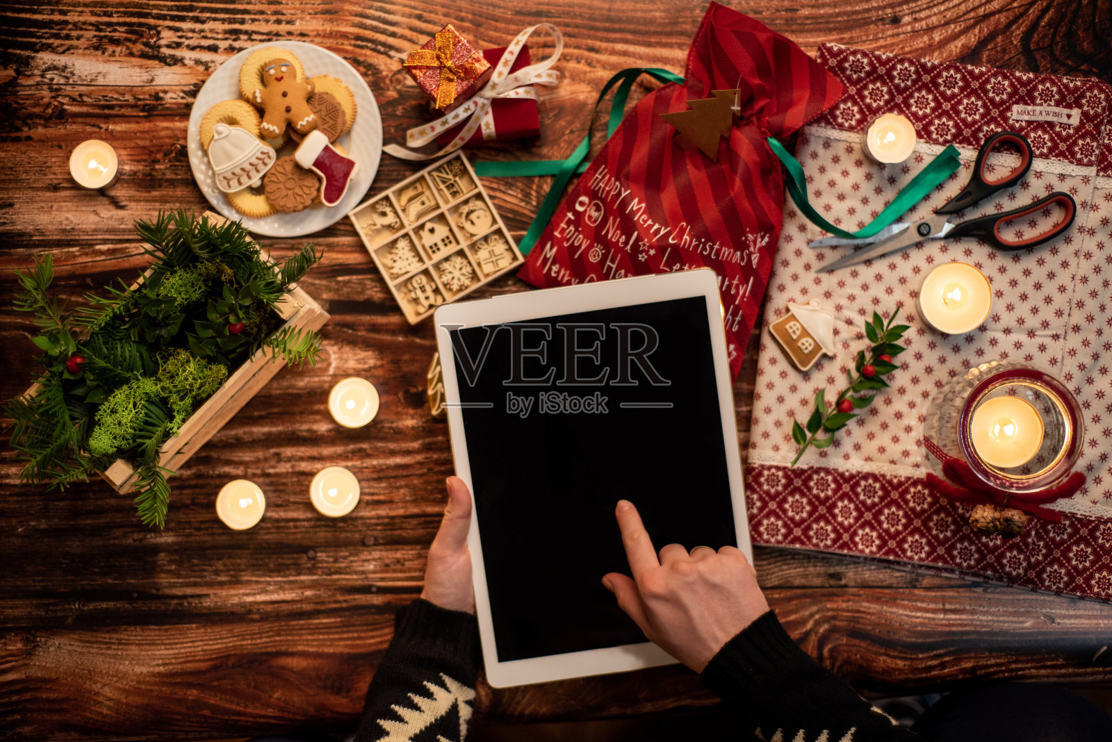 俯视图的女人的手握着数字平板电脑的桌子满是圣诞节装饰照片摄影图片