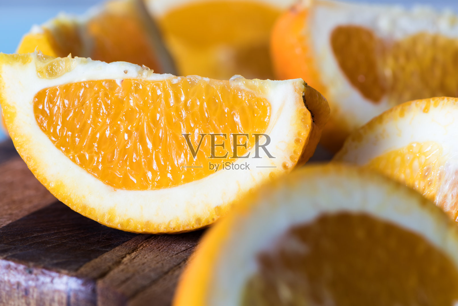 厨房砧板上的橙色楔子在蓝色背景上照片摄影图片