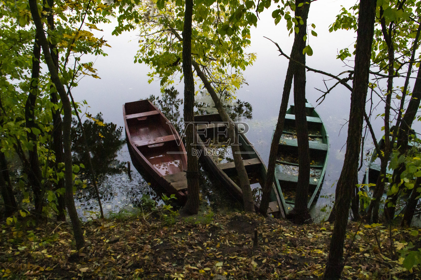 空船被绑在河边。秋天的风景与树木和船只照片摄影图片