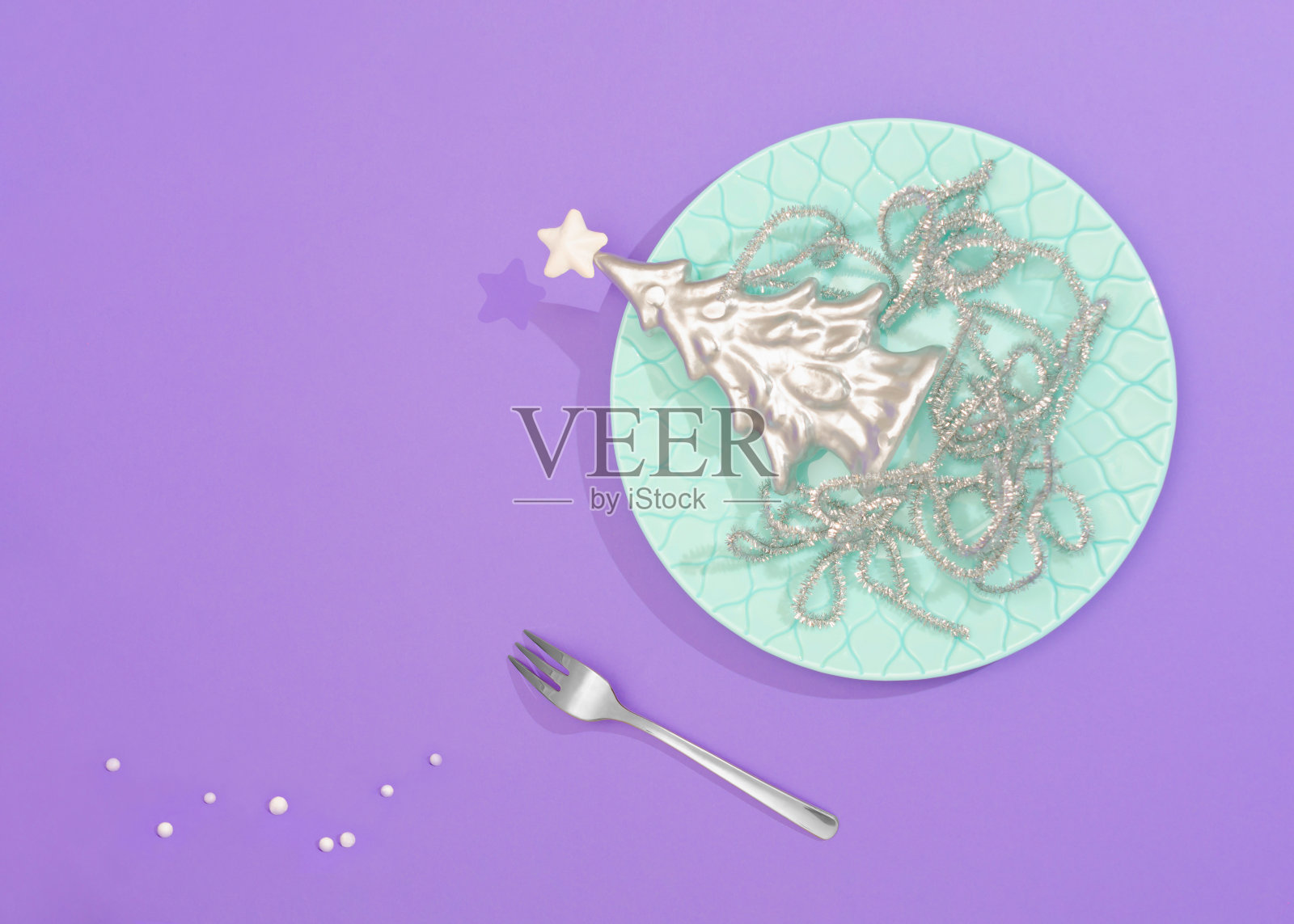 抽象银色甜品构图。银色的圣诞树和银色装饰的意大利面被放在一个时髦的盘子里。淡薄荷、银色和淡紫色的混合物很吸引眼球。照片摄影图片