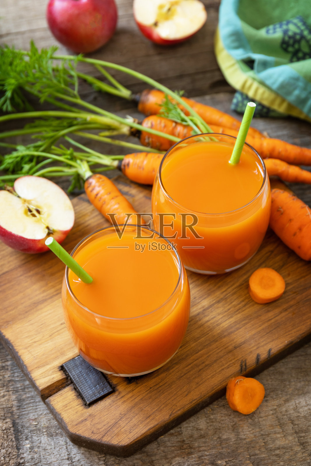 新鲜天然果汁,健康食品理念。一罐新鲜的苹果和胡萝卜汁放在一张质朴的木制桌子上。照片摄影图片