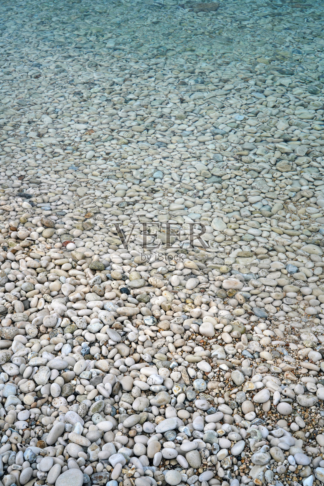 平静的蓝绿色的大海和鹅卵石的海滩照片摄影图片
