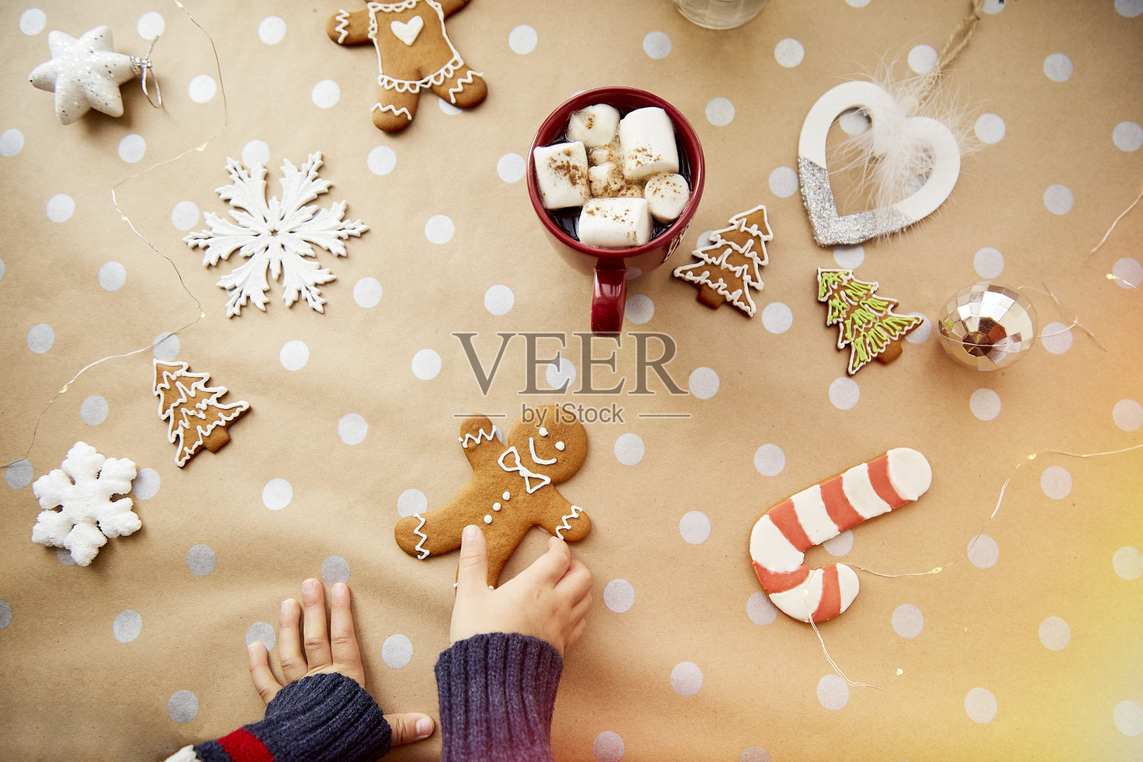 圣诞自制姜饼曲奇在孩子的手与热饮料和棉花糖圣诞装饰之间。唯美的圣诞氛围,家居舒适温馨的理念照片摄影图片
