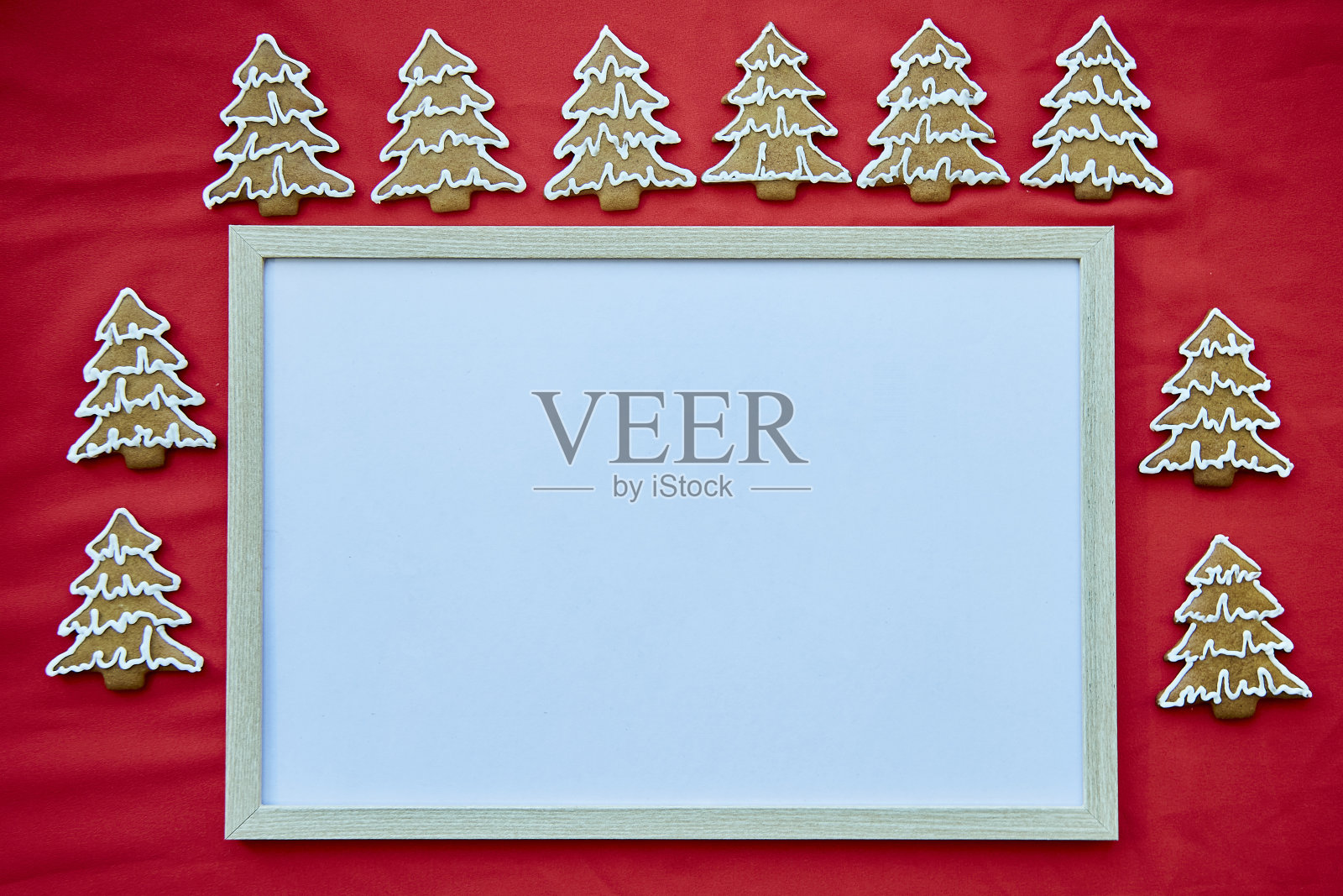 圣诞自制姜饼饼干与模拟框架。红色织物上的节日美学卡片。圣诞节的气氛。圣诞快乐,家庭舒适概念照片摄影图片
