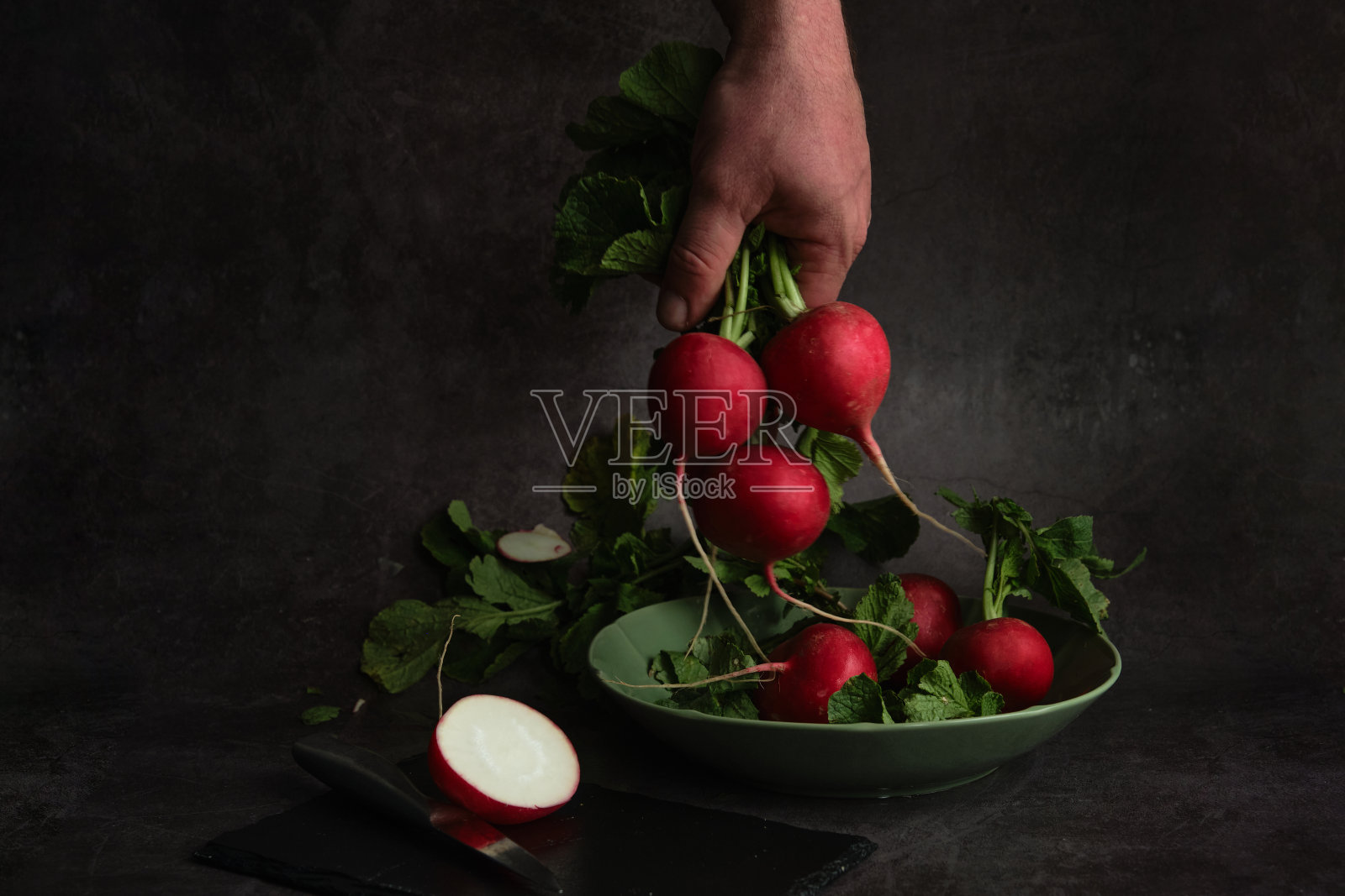 一个男人手里拿着一串新鲜的萝卜照片摄影图片