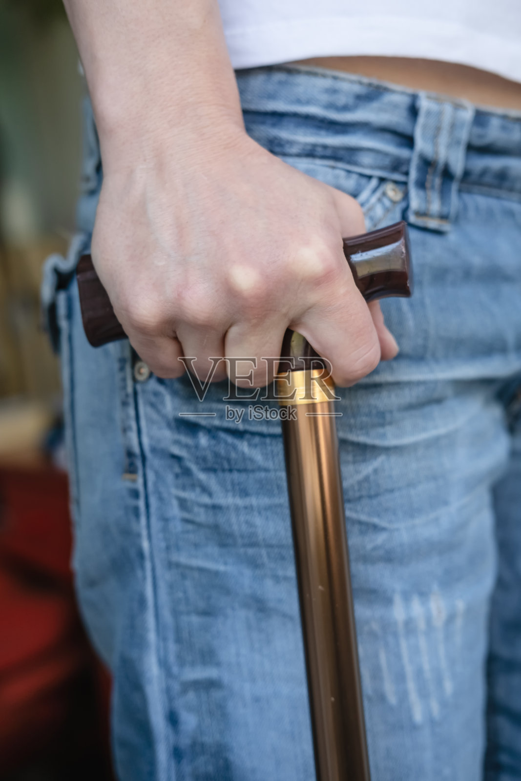 一位年轻女子的手,她拄着拐杖,在运动受伤后被迫暂时依靠拐杖行走。照片摄影图片