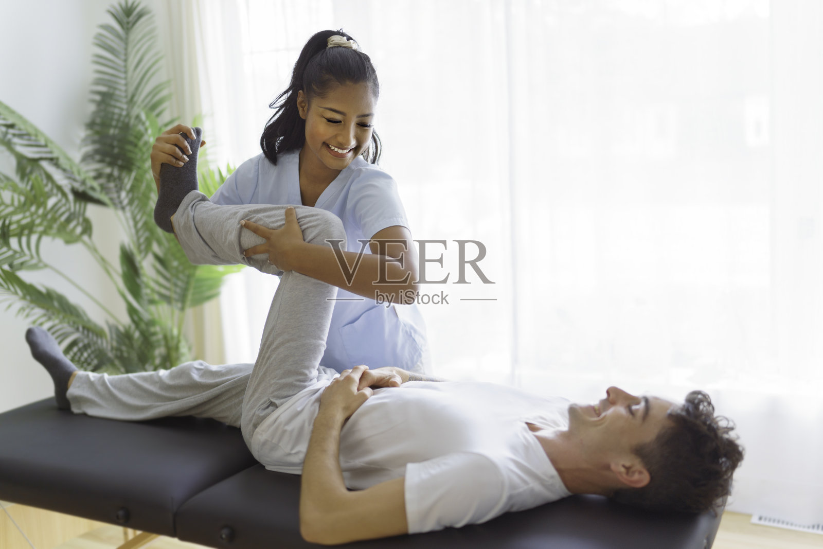 年轻女性物理治疗师在物理诊所与客户照片摄影图片