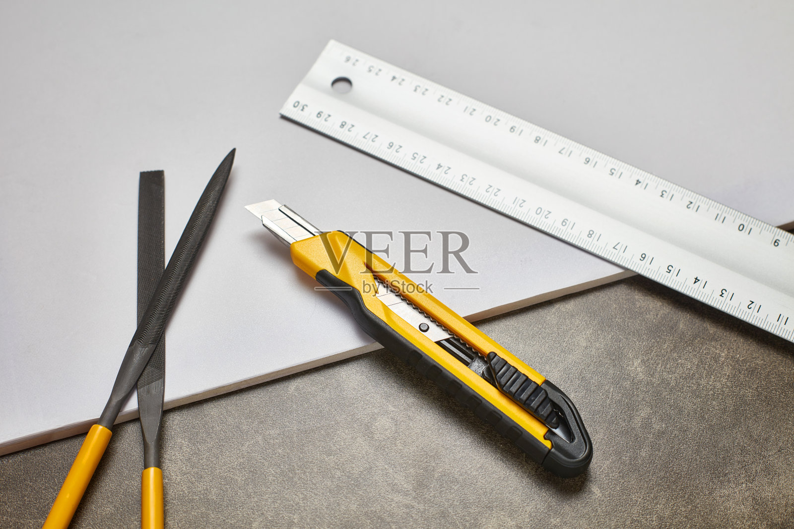 黄色的艺术刀和白色的尺子在大理石桌子上照片摄影图片