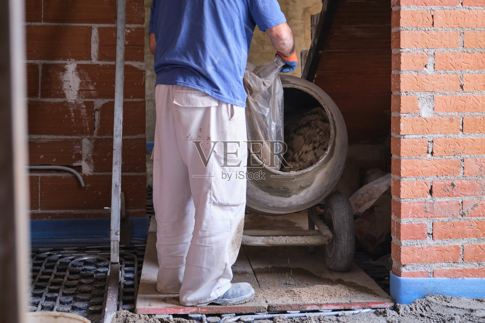 建筑工人正在往混凝土搅拌机里装沙袋。照片摄影图片