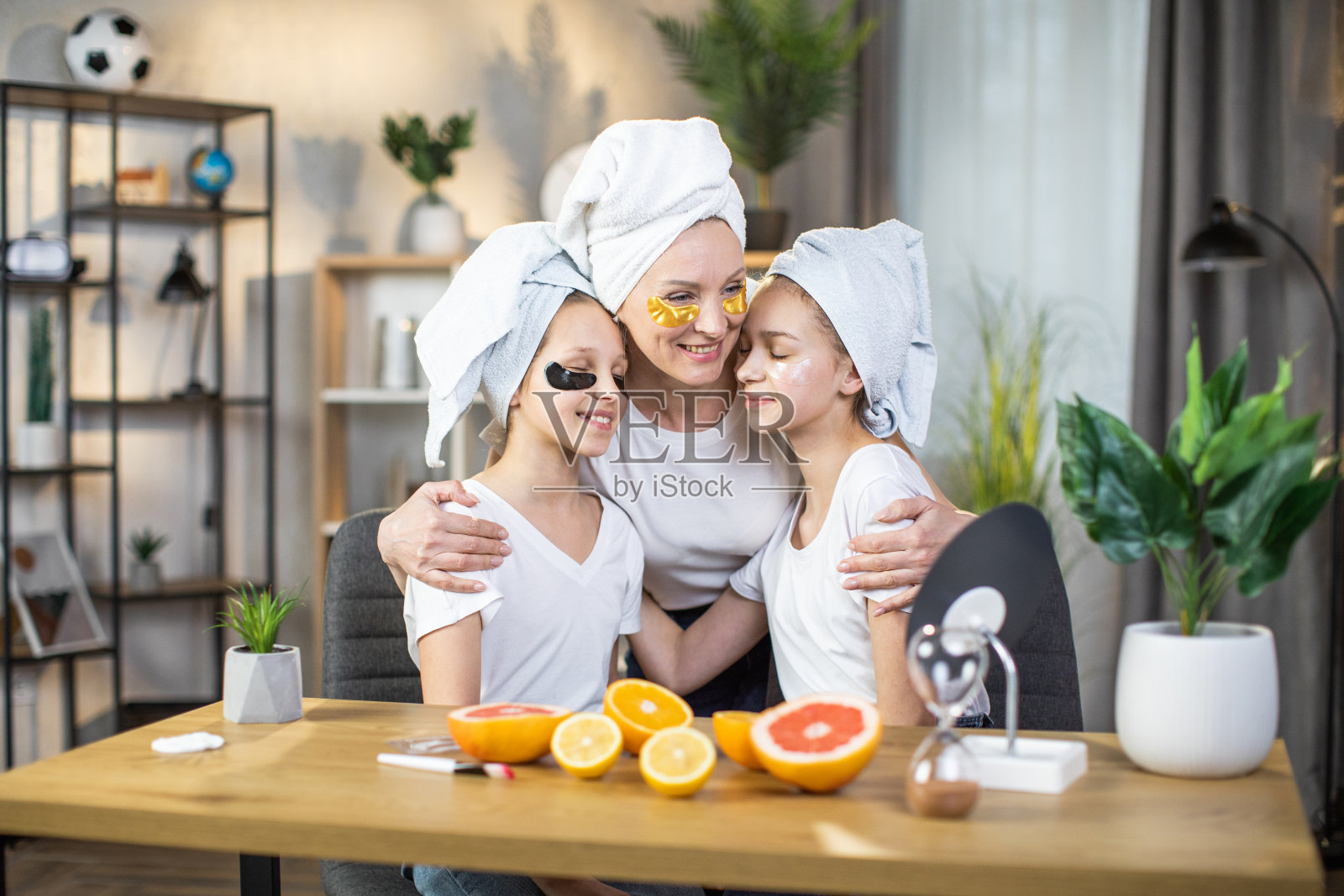 带着女儿的母亲在眼部使用胶原蛋白垫照片摄影图片