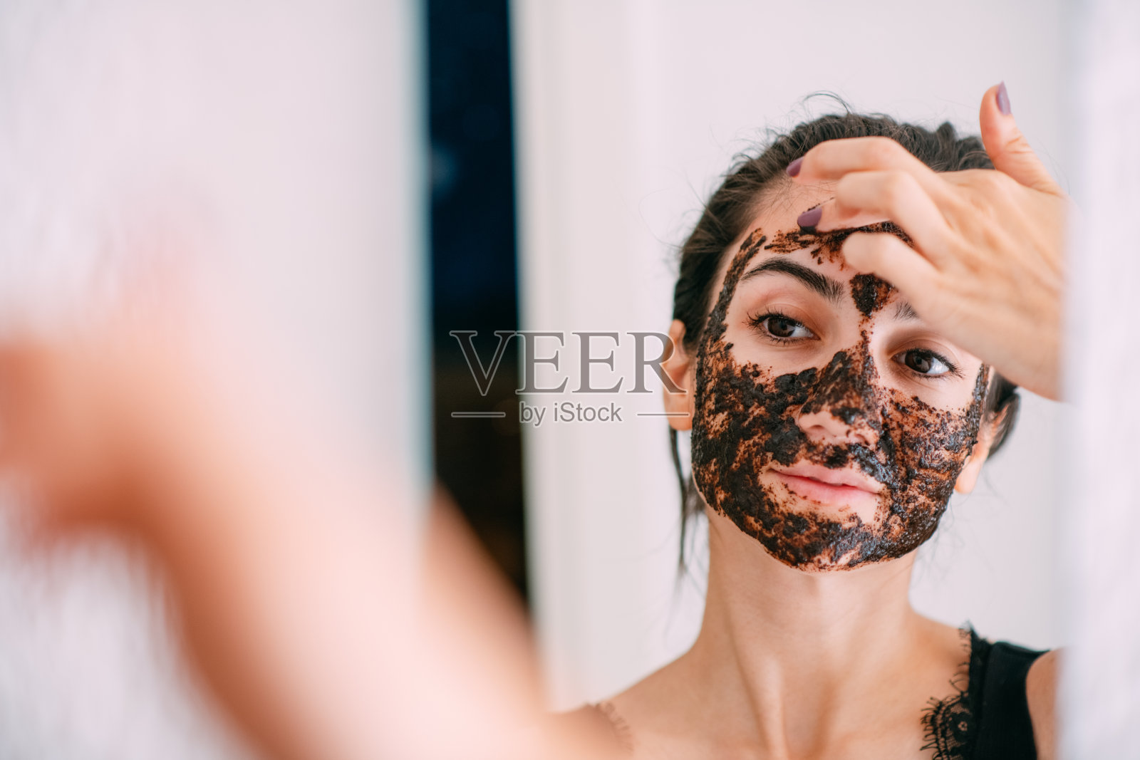 年轻女子在镜子前做面膜照片摄影图片