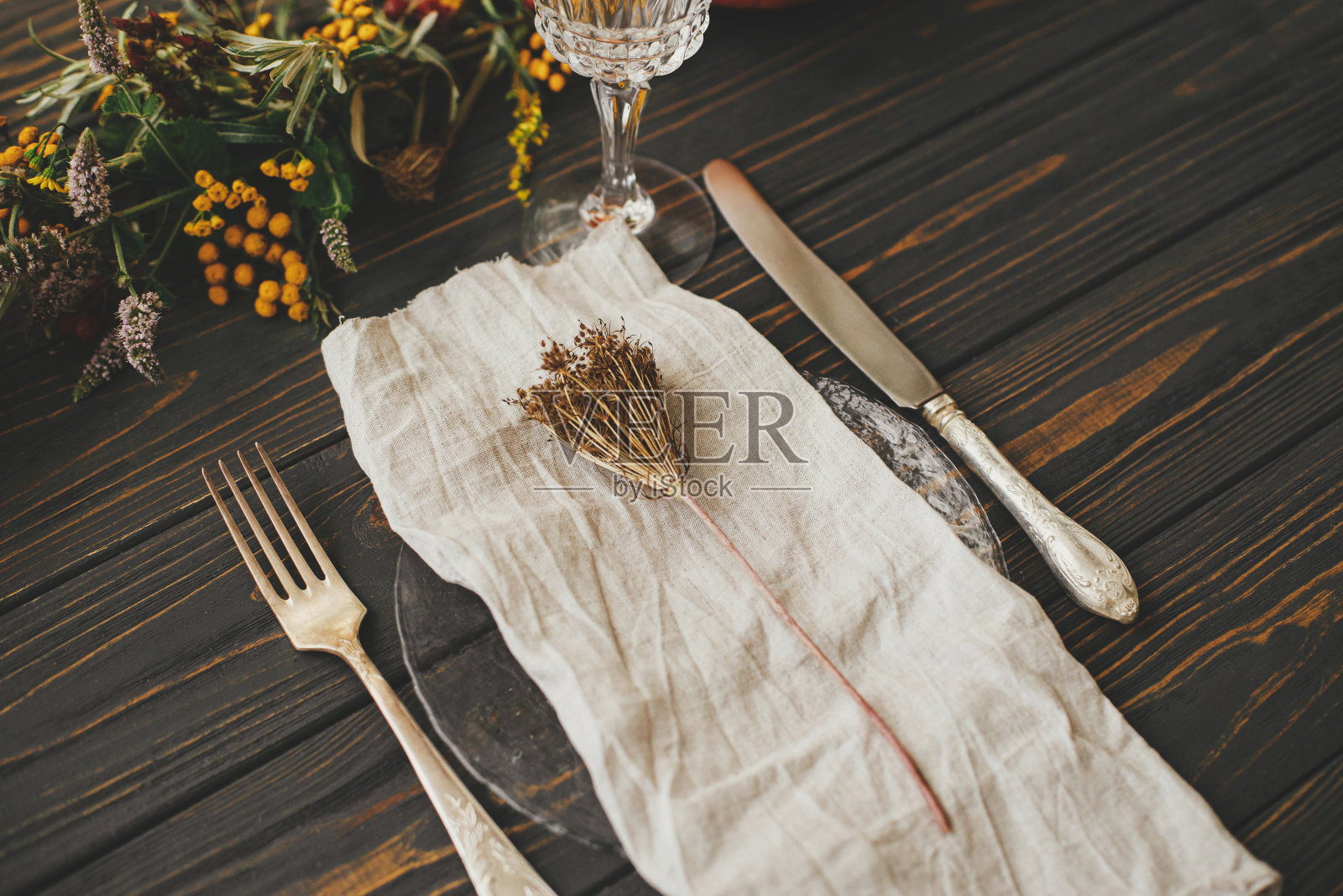 感恩节晚餐质朴的餐桌布置。现代的盘子与复古的餐具,亚麻餐巾,香草木制桌子上的南瓜和秋天的鲜花安排。生态友好的农家秋季餐饮照片摄影图片