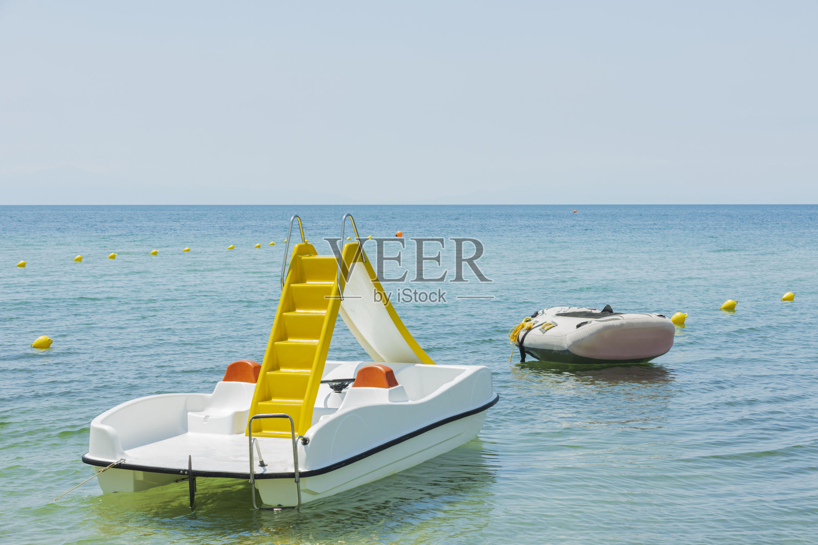 近景的水滑梯双体船和橡胶船在美丽的自然背景海岸。希腊。照片摄影图片