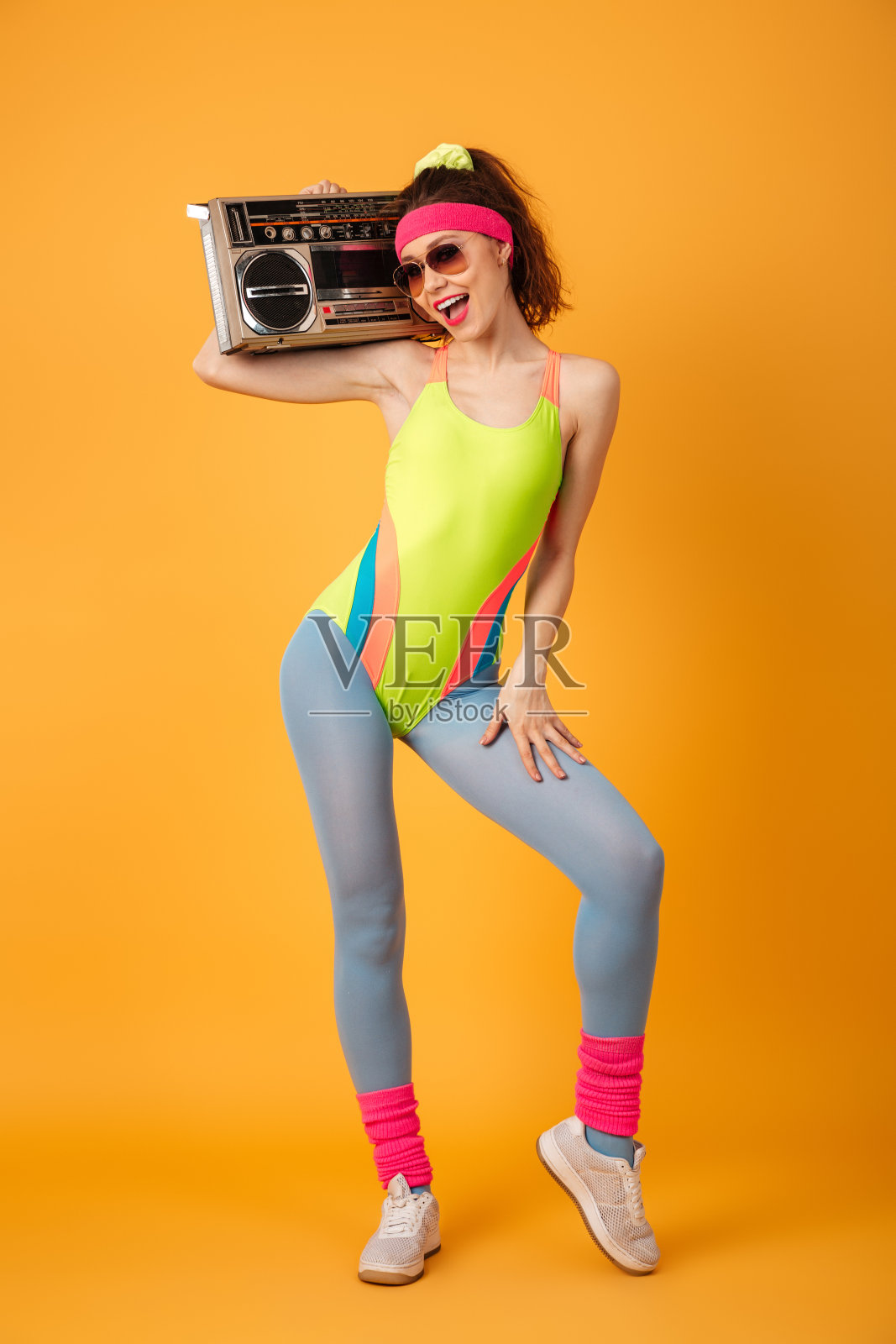 快乐美丽的年轻女运动员站着拿着旧录音机照片摄影图片