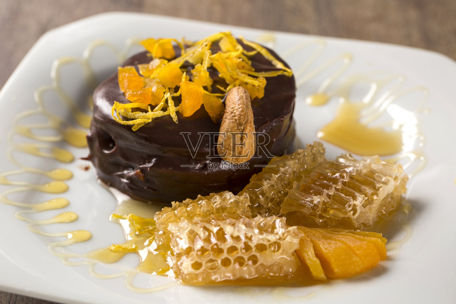 Lebkuchen,上面的盘子里放着杏片,还有巧克力和一块蜂房盖在木质表面上。照片摄影图片