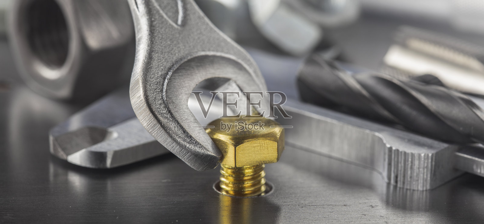 扳手用来拧紧钢坯中的黄铜螺栓。扳手、螺栓、螺钉和螺母。照片摄影图片