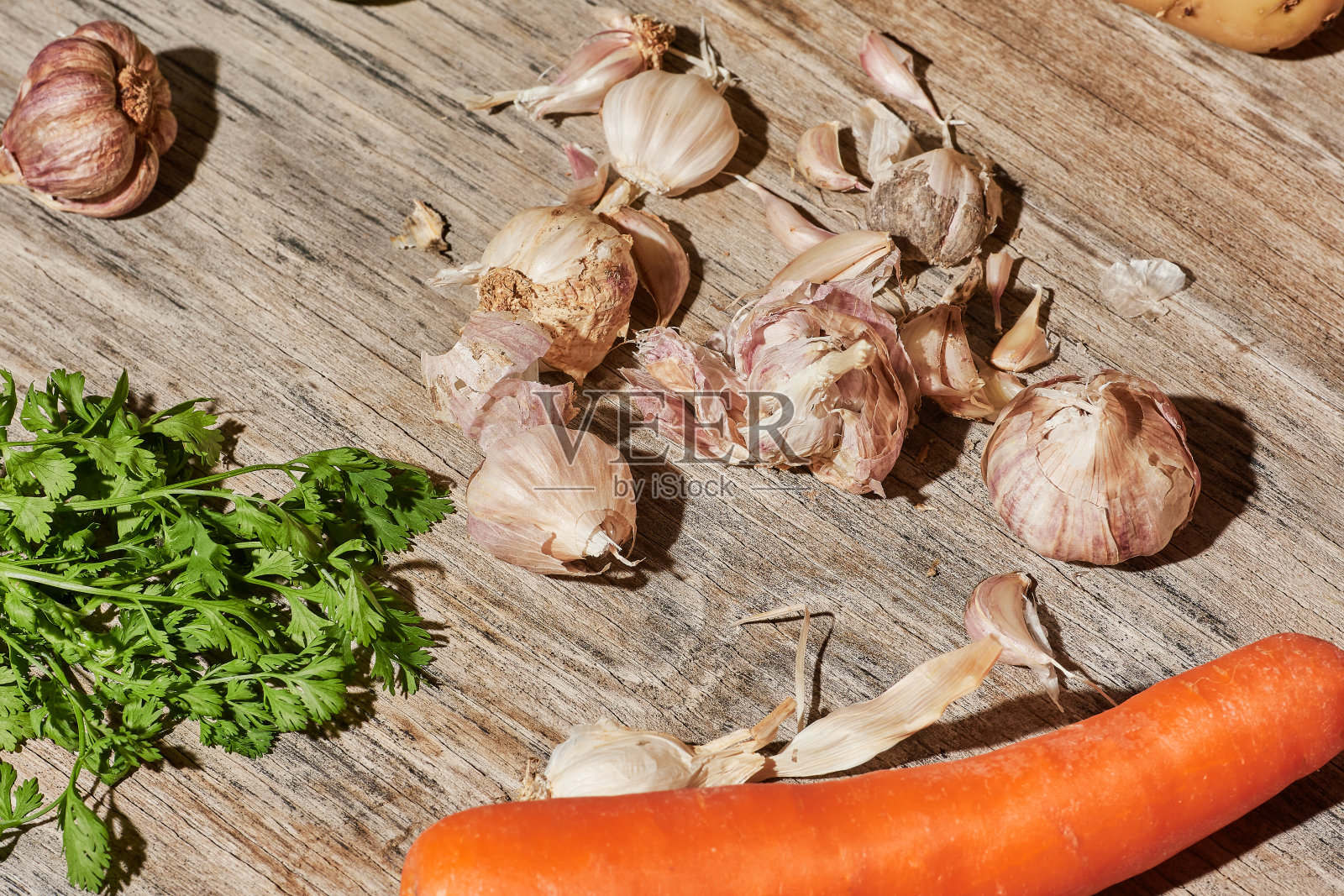 食品的背景。只是食物。微距摄影。特写镜头。大蒜,土豆,柠檬,西红柿,胡萝卜,香菜在木制背景上硬光。照片摄影图片