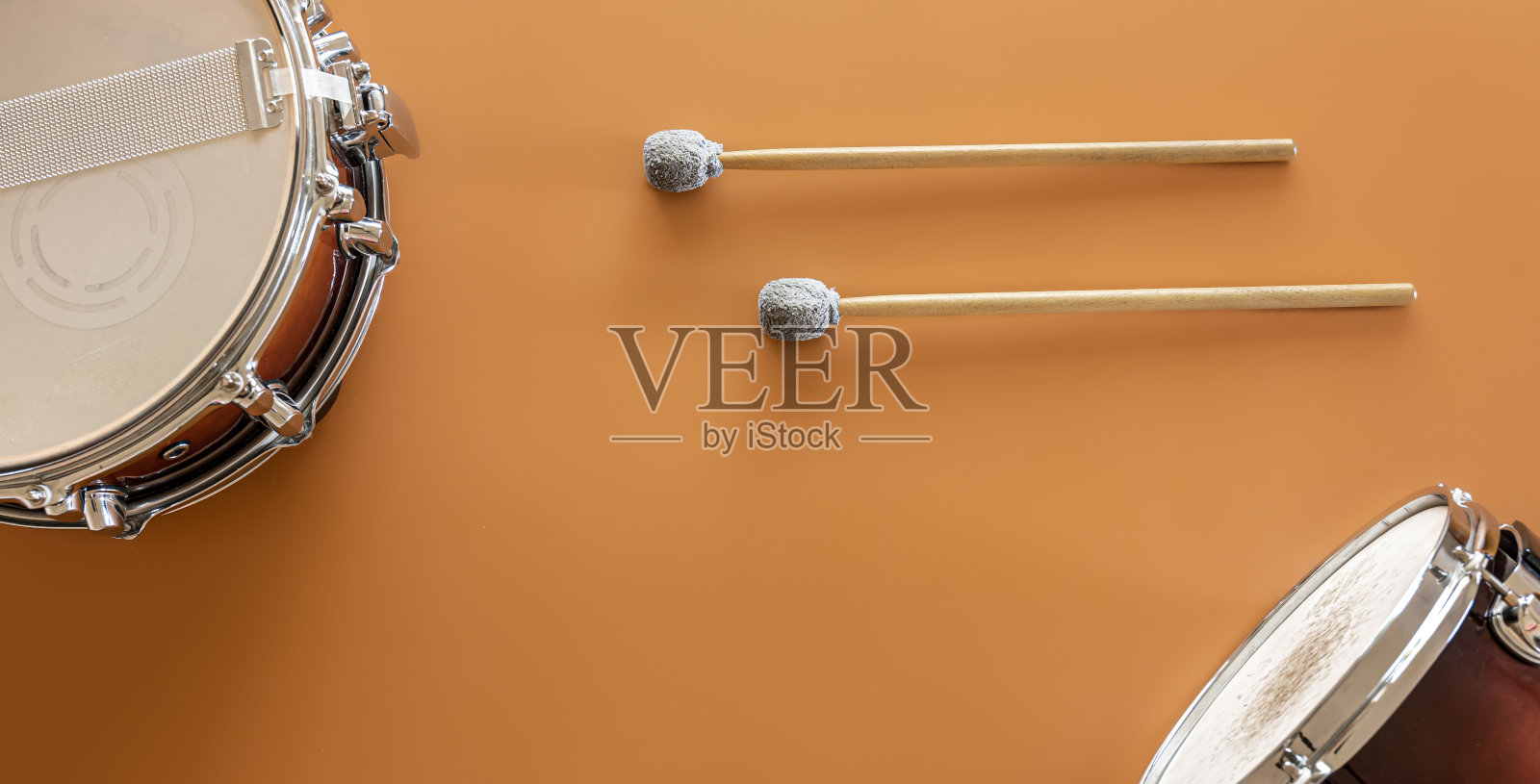 鼓和鼓棒在一个棕色背景,俯视图。照片摄影图片