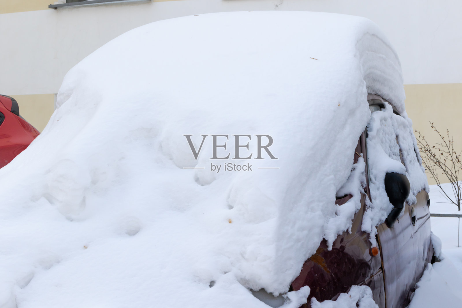 冬天里,一辆红色的废弃汽车停在一层厚厚的雪下,天气晴朗,结了霜照片摄影图片