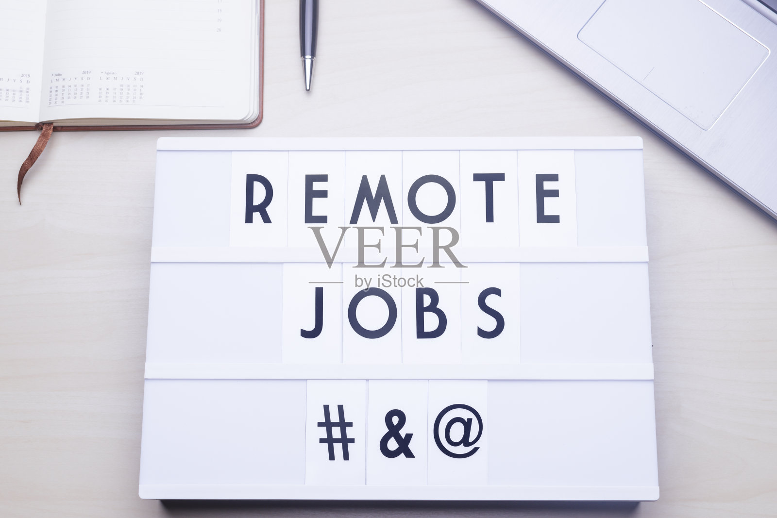 居家办公带有带有“REMOTE JOBS”字样的lichtbox的工作区表。照片摄影图片