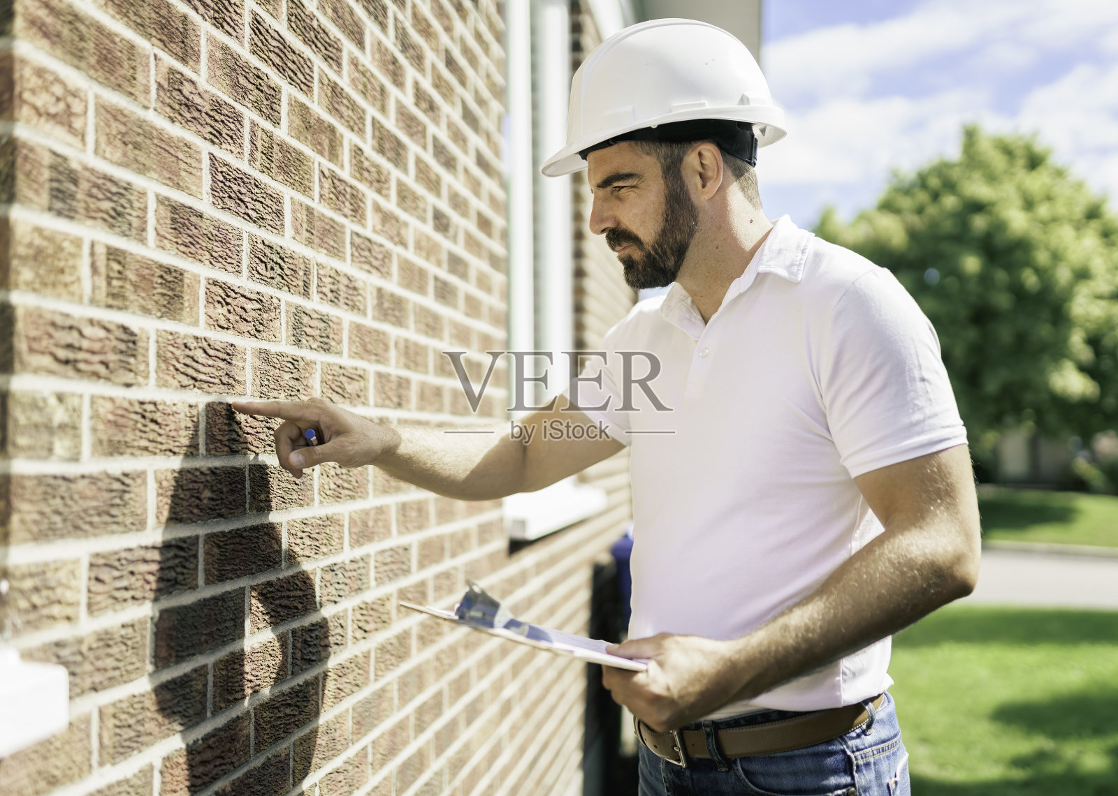 戴着白色安全帽的人拿着写字板检查房子照片摄影图片