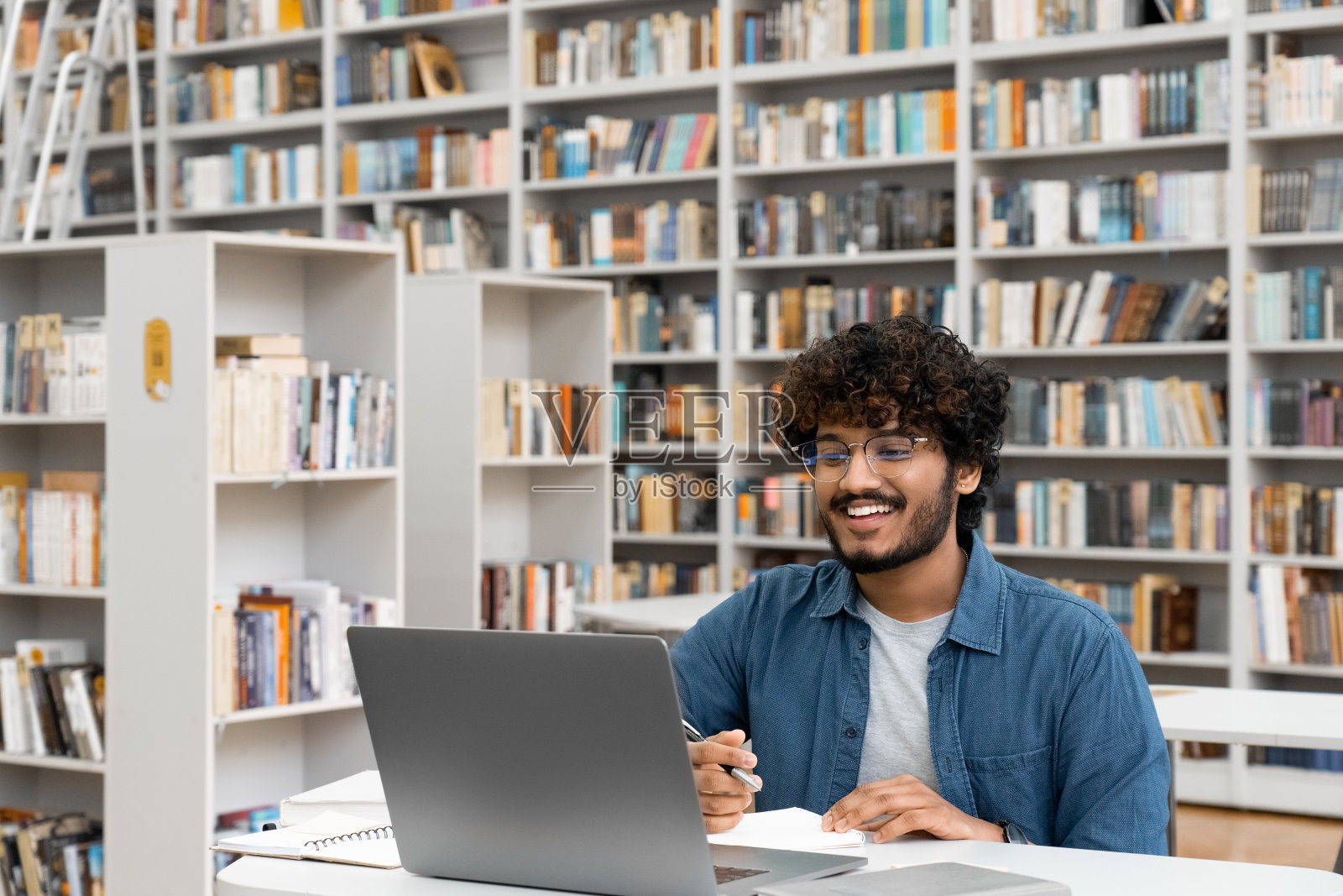 在大学图书馆学习的男学生使用笔记本电脑进行视频通话照片摄影图片