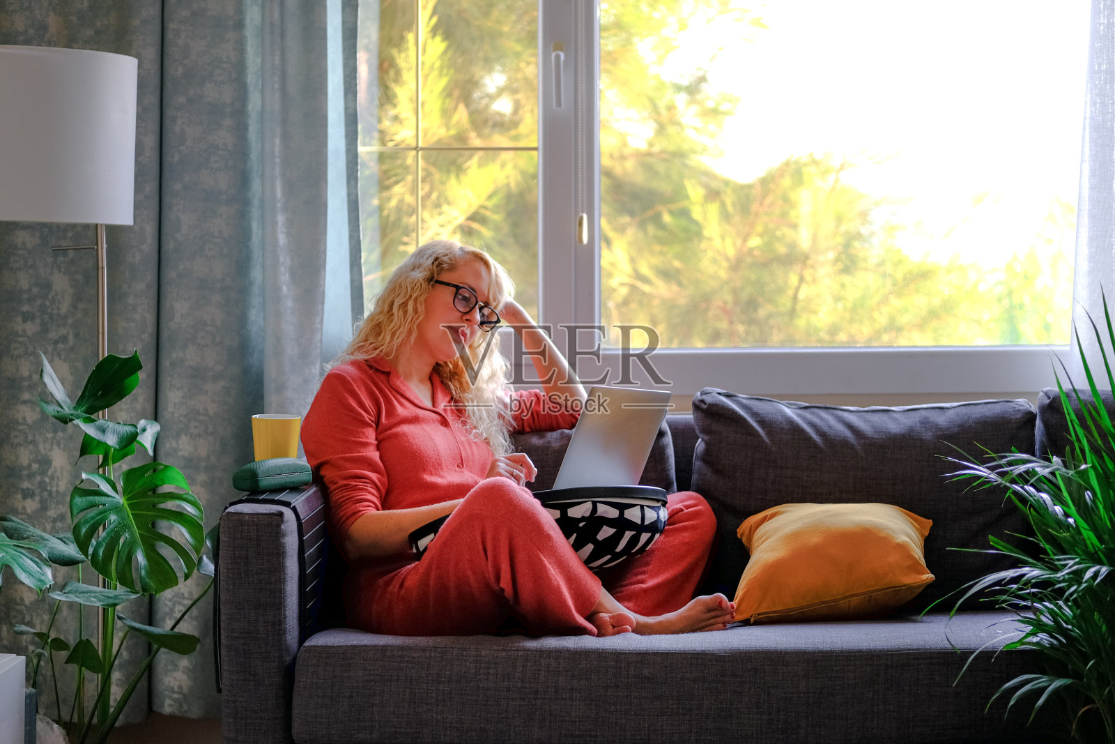 金发女人戴着眼镜,拿着笔记本电脑打电话。照片摄影图片