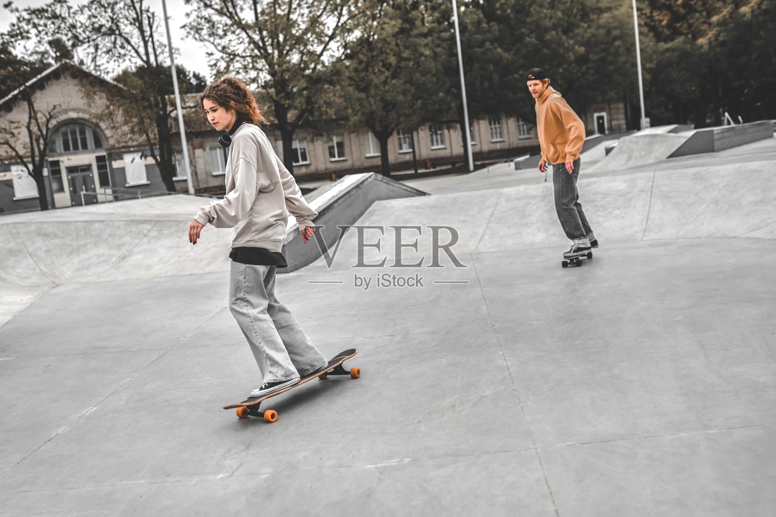女孩在前面玩滑板,男孩在后面照片摄影图片
