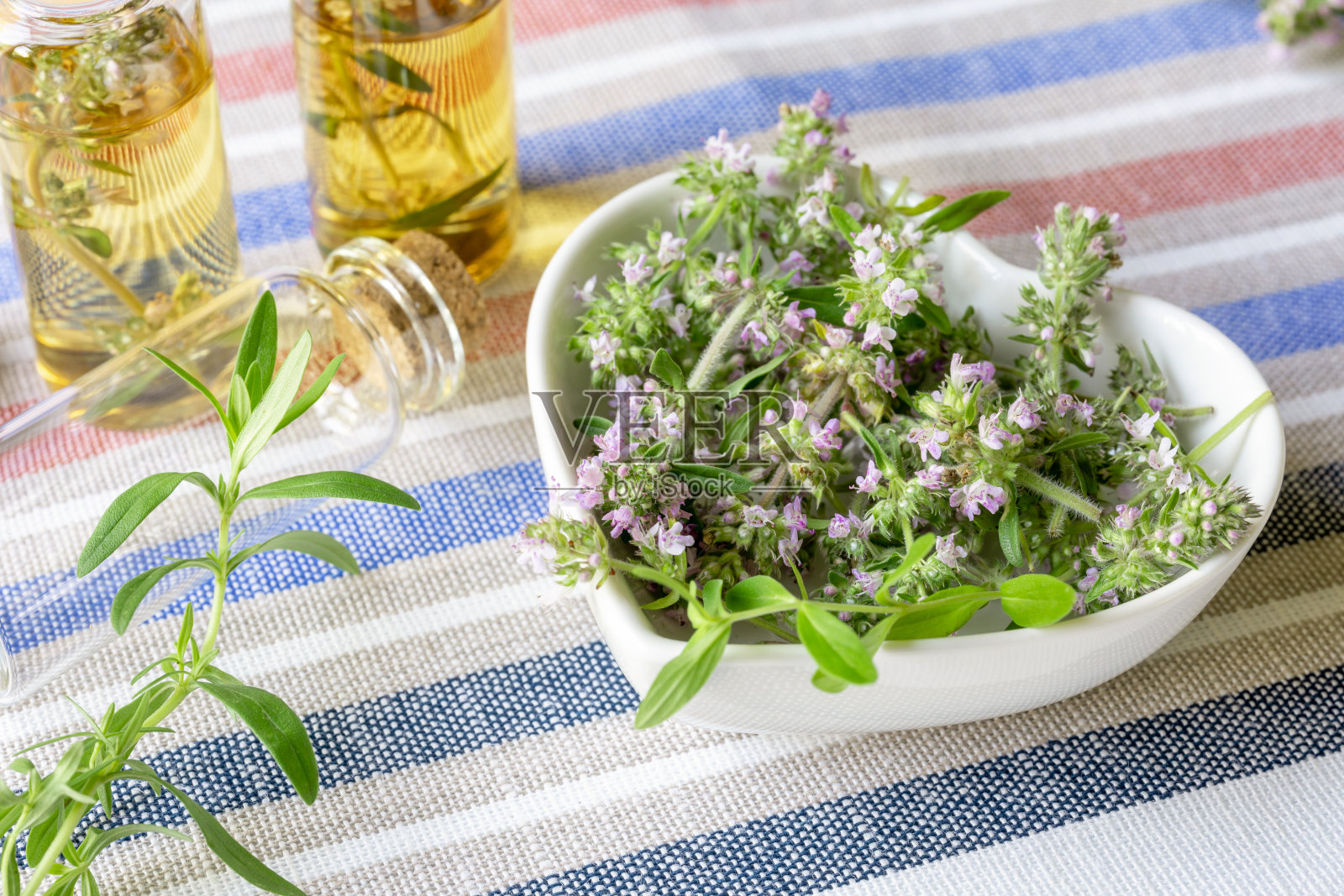 将开花的百里香切成片,放在白色心形的盘子里,加入百里香精油。替代医学的概念照片摄影图片