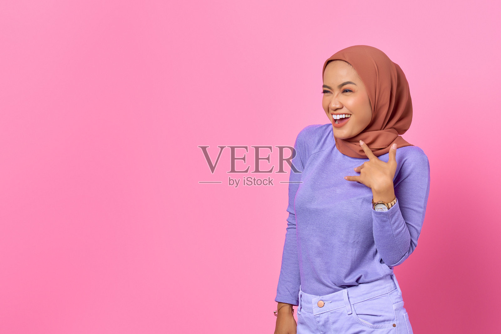 开朗的年轻亚洲女人的肖像在粉红色的背景上看着一边照片摄影图片